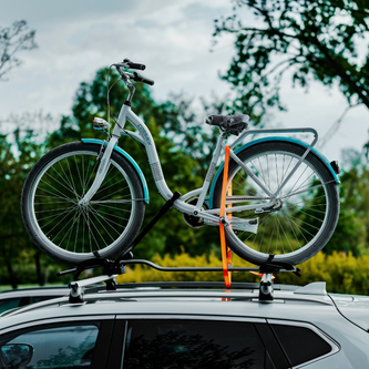 	Aerodynamic roof-mounted bike carrier with fork-mount system and wheel straps securing a road bike at highway speeds