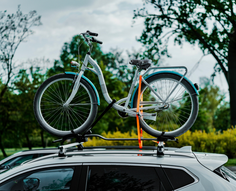 	Aerodynamic roof-mounted bike carrier with fork-mount system and wheel straps securing a road bike at highway speeds