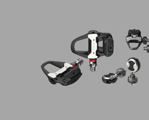 Road cyclist climbing with power meter pedals syncing metrics to head unit for training analysis