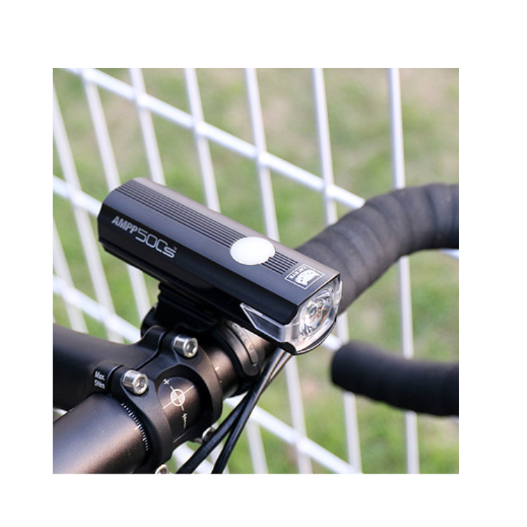 Close-up of the AMPP500s bike light, highlighting its sleek design and powerful LED beam, mounted on the bike's handlebar for effective night cycling.