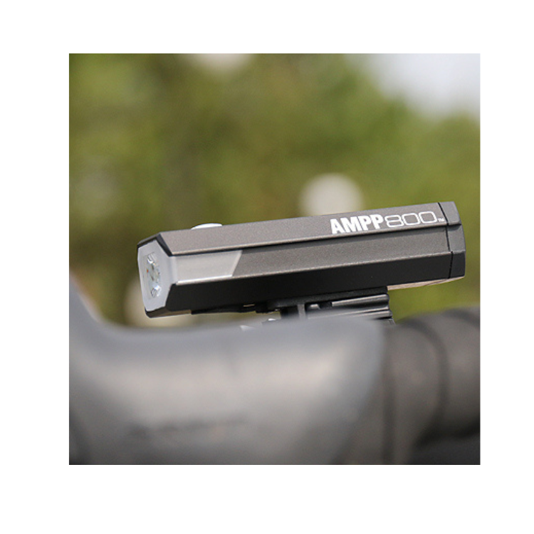 Close-up of the AMPP800 bike light attached to a handlebar, highlighting its robust build and advanced LED technology for optimal brightness.