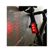 Cateye Tight Kinetic rear light mounted on a bicycle, casting a red light on the wall, demonstrating its bright visibility for cycling safety.