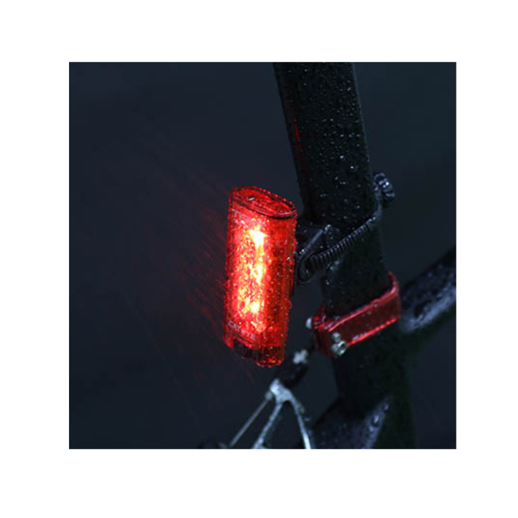 Cateye Tight Kinetic rear light mounted on a bike, showing its bright red light while exposed to rain, highlighting its water-resistant feature for all-weather cycling.