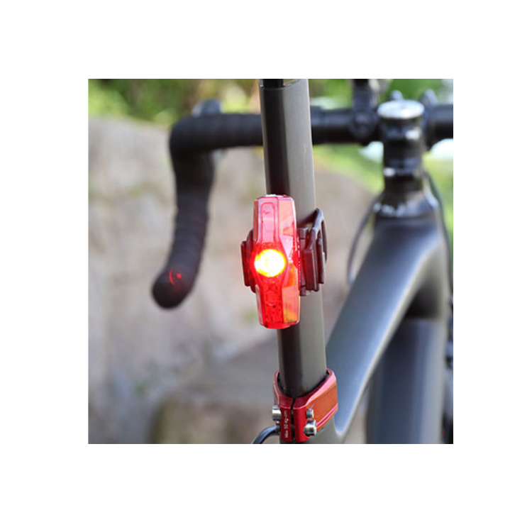 Cateye VIZ100 rear bike light mounted on a bicycle seatpost, illuminated with red light for better safety and visibility while cycling in low-light conditions.