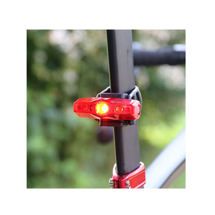 Cateye VIZ100 rear bike light mounted on a bicycle seatpost, displaying both red and yellow lights for enhanced visibility and safety while riding.