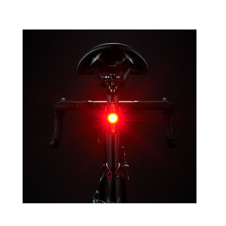  Cateye VIZ150 rear bike light with red LED on a bike saddle, glowing brightly in low light.