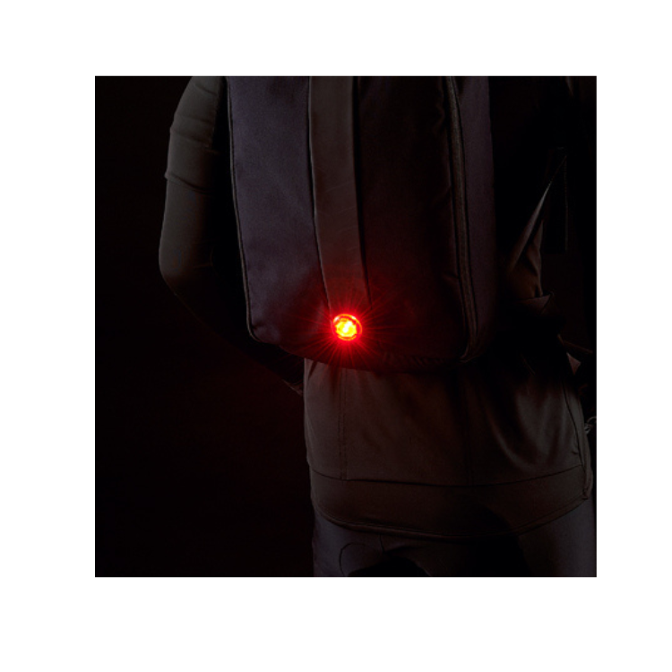 Cateye wearable mini LED light attached to a backpack, providing added visibility for pedestrians and cyclists.