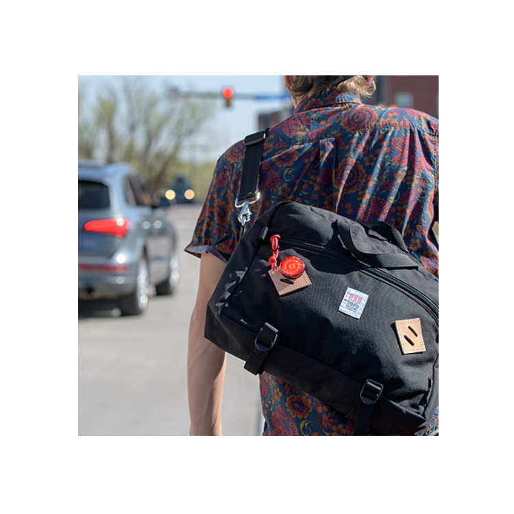 Cateye wearable mini LED light attached to a backpack, providing extra visibility for cyclists or pedestrians in low-light conditions.