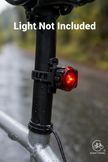 Red bicycle tail light attached to a bike frame with a blurred natural background