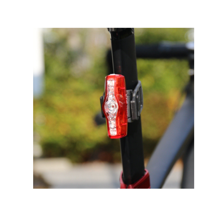 Cateye VIZ150 rear bike light glowing in red, mounted on the rear of a bicycle, providing daytime visibility for cyclists.