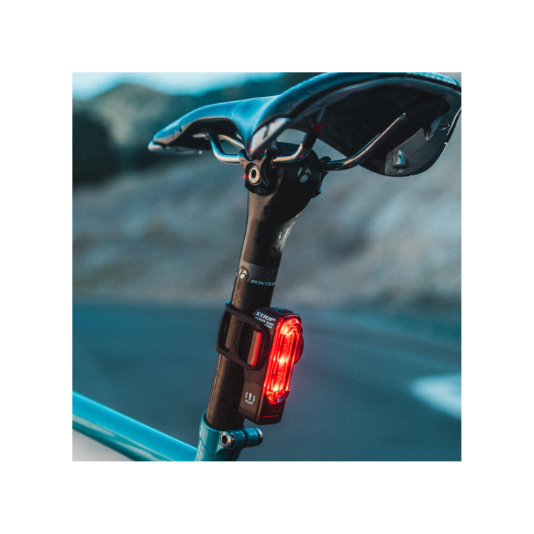Lezyne Strip Alert 300 Pro rear bike light mounted on the seat post, showing red LED lights with alert mode for better visibility.