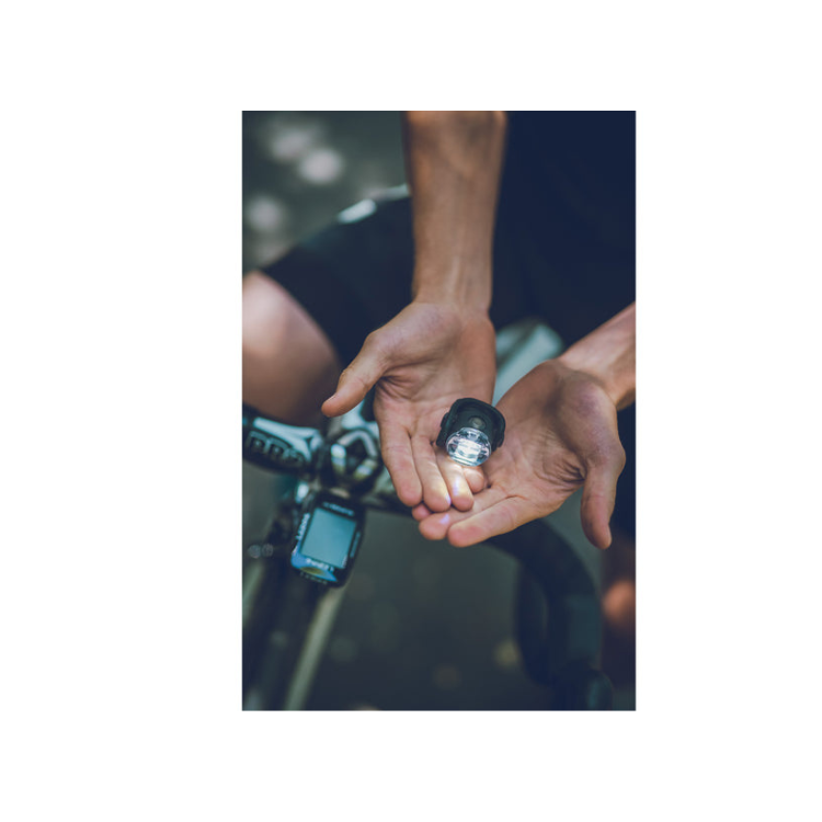 Cyclist holding a Lezyne wearable bike light in their hands, showcasing its small size and portability for easy attachment during rides.