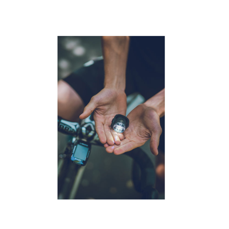 A rider holding Lezyne's wearable mini bike light in hands, showcasing its compact design and versatility for secure attachment.