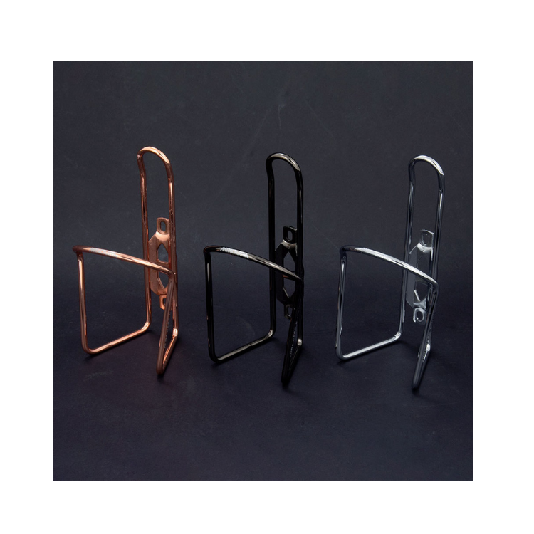 Trio of Lezyne CNC bottle cages in copper, black, and chrome finish on dark background.
