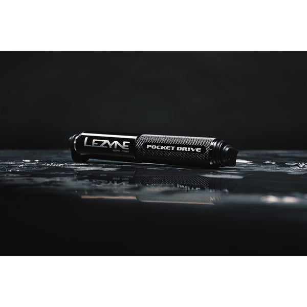 Black Lezyne Pocket Drive mini pump resting on a reflective wet surface with water droplets.