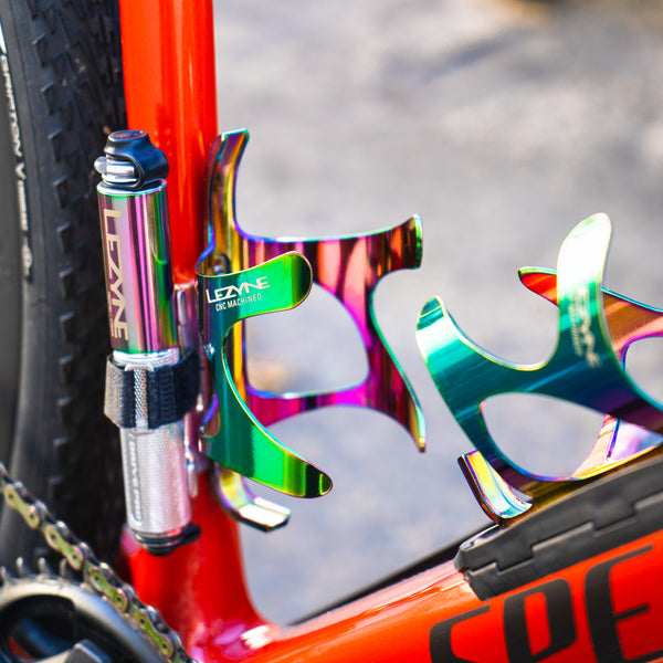 Close-up of a Lezyne Pocket Drive Pro mini pump in oil-slick finish attached to a red bike frame with rainbow bottle cages.