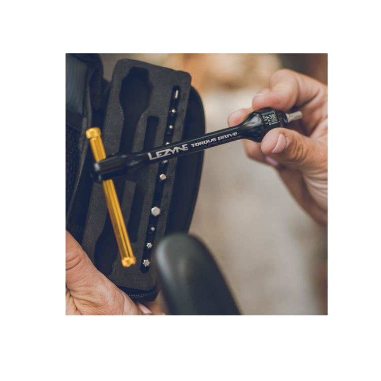Hand holding Lezyne Torque Drive tool while selecting bits from its carry case.