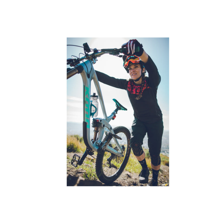 Rider pushing mountain bike uphill equipped with Lezyne bottle cage on frame.