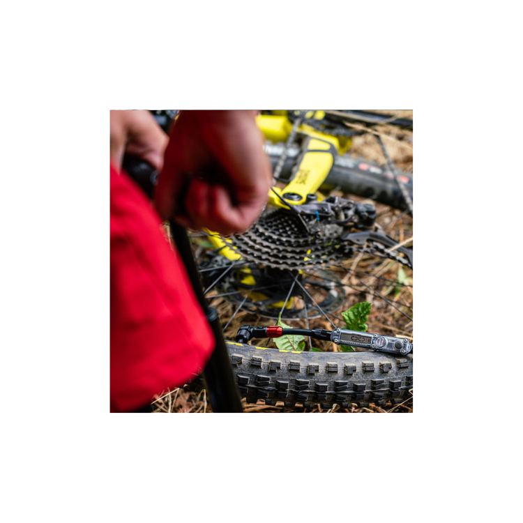 Close-up of a mountain bike tire being inflated trailside with a compact digital floor pump